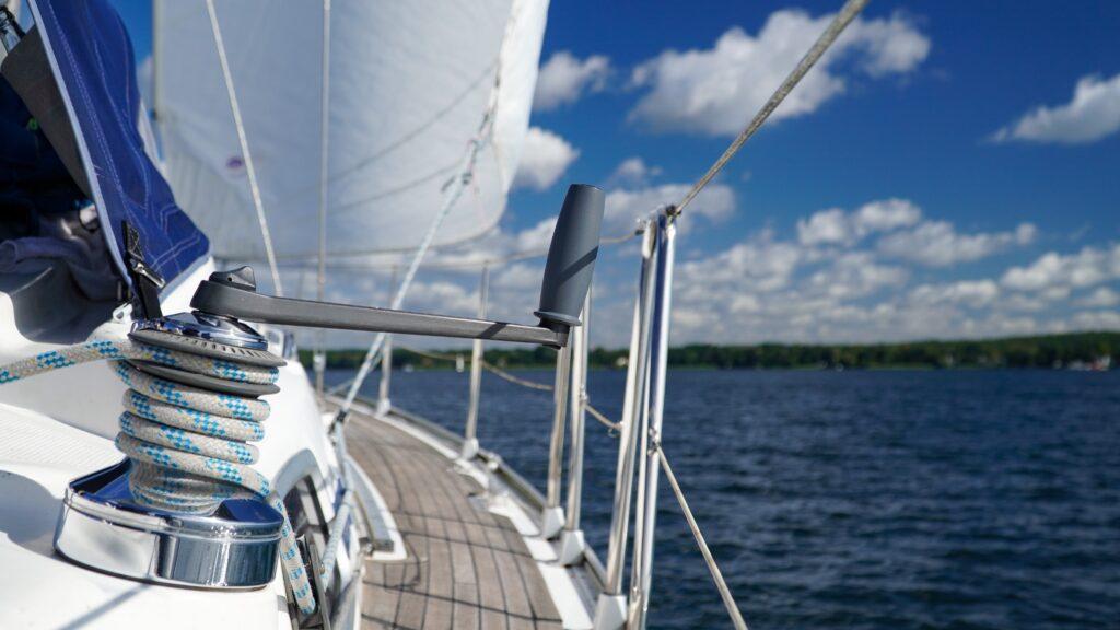 Segelyacht unter weißen Segeln auf dem Scharmützelsee, im Hintergrund ist ein blauer Himmel mit weißen Wolken zu sehen
