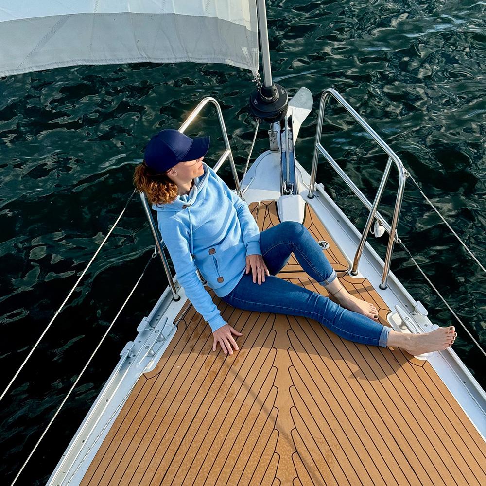 Frau sitzt vorn am Bug einer Segelyacht