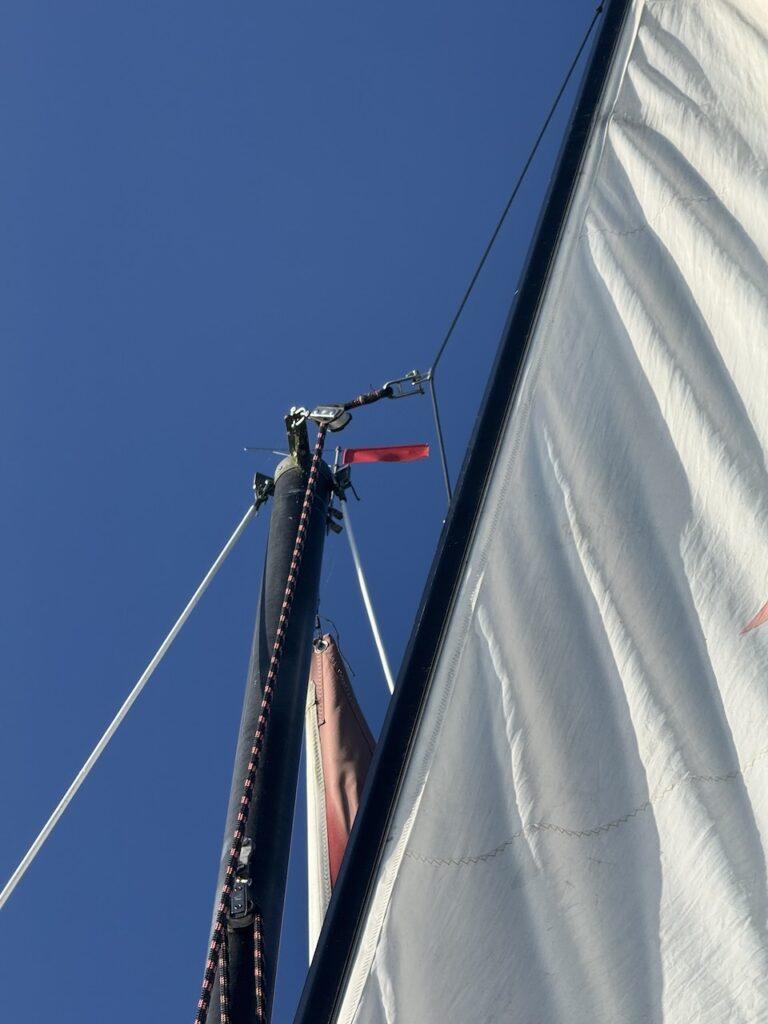 Masttop mit Verklicker einer Kieljolle vor blauem Himmel